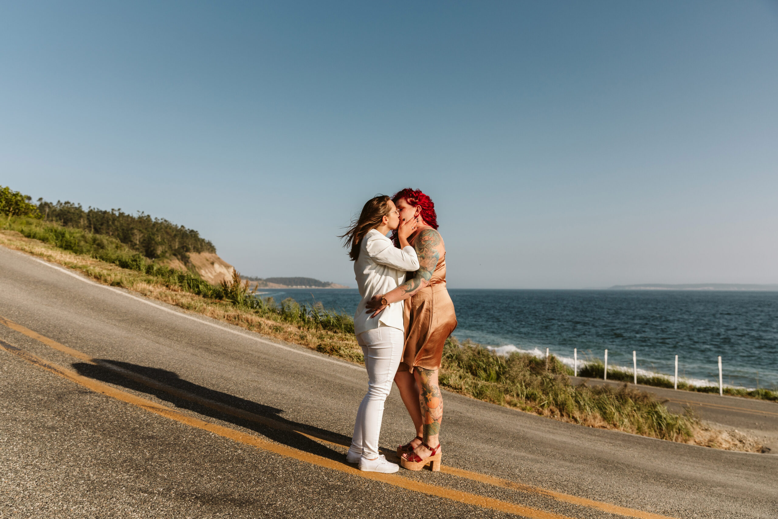 Lesbian couple kissing on the cliffs by the sea near Whidbey Island