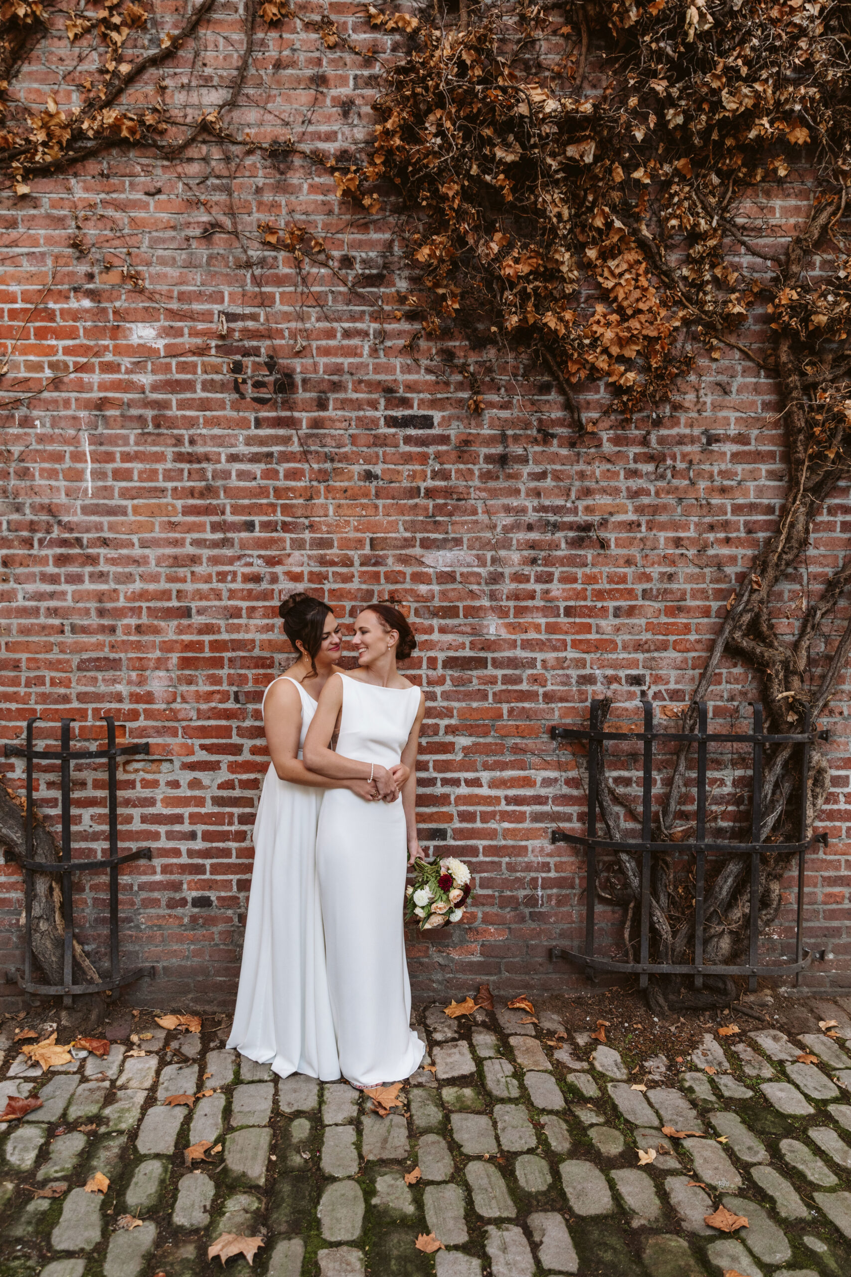 Two brides intimate wedding portraits by brick wall in pioneer square seattle